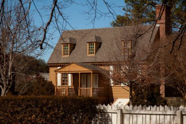 Virginia, ABD 02 / 24 / 2014: Tuğla baca, ahşap pencere panjurları, verandası ve çatı pencereleri olan bir sömürge dönemi evi. Bu model ev Colonial Williamsburg temalı müzede bulunmaktadır..