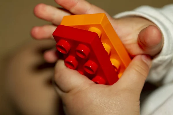 Close up image of an infant baby\'s hands as he or she is trying to interlock two toy bricks. Image is useful to demonstrate motor development, fine motor skills, balance, precision, baby growth themes