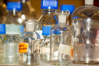 Oxford, İngiltere 10 / 24 / 2009: Bilimsel bir laboratuvarda kullanılan bir grup şişenin yakından görüntüsü. Bu borosilikat cam şişeler ısıya ve aşınmaya dayanıklıdır ama mavi kapaklar aşınma ve yırtık gösteriyor..