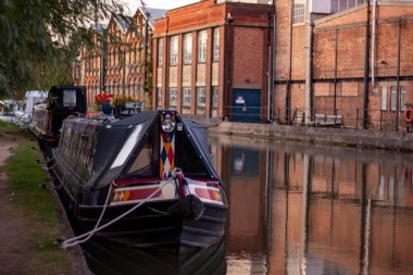 Oxford 'da bir kanala demirlenmiş dar bir kayıkhaneye yakından bakın. Birkaçı sıralanmış ve kanalın diğer tarafında suyun yansıması olan tuğladan binalar var.. 