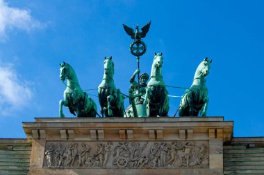 Berlin 'deki Brandenburg kapısının tepesinde duran kuadriganın yakın görüntüsü. Heykelde, Prusya kartal standardını taşırken dört atlı bir at arabası süren bir tanrıça (Victoria) yer alıyor.