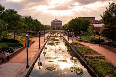 Frederick, MD, USA 08 / 14 / 2020: Frederick şehir merkezindeki Carroll Creek Parkı 'nın öğleden sonra manzarası. Bir dere, insanların aşağı yukarı yürüdüğü kaldırım taşlı caddelerden geçiyor. Kasabada popüler bir yer..