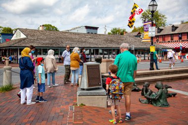 Annapolis, MD 08 / 21 / 2020: Annapolis 'in tarihi rıhtımında Kunta Kinte-Alex Haley anıtı çevresindeki insanların görüntüsü. Beyaz bir adam ve torunu ve maske takan Müslüman bir aile görüldü..