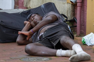 Annapolis, MD 08 / 21 / 2020: Evsiz bir Afrikalı Amerikalı bavulunun kaldırımında uyuyor. Elbiseleri dikenli ve kirli..