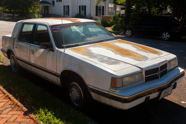 Chestertown, MD, USA 08 / 30 / 2020: Sokağa park edilmiş çok eski, paslı Dodge Dynasty marka bir arabanın yan görüntüsü. Her tarafı paslanmış, boyası ve aşınması var.