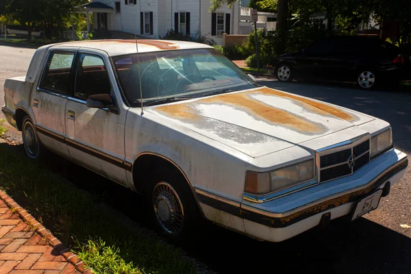Chestertown, MD, USA 08 / 30 / 2020: Sokağa park edilmiş çok eski, paslı Dodge Dynasty marka bir arabanın yan görüntüsü. Her tarafı paslanmış, boyası ve aşınması var.