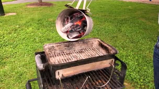 一位妇女正在把燃烧的炽热的煤块从烟囱里转移到花园的烤架上 这是一种带有手柄的圆柱形金属工具 用于烧烤前点燃煤块和煤块 — 图库视频影像