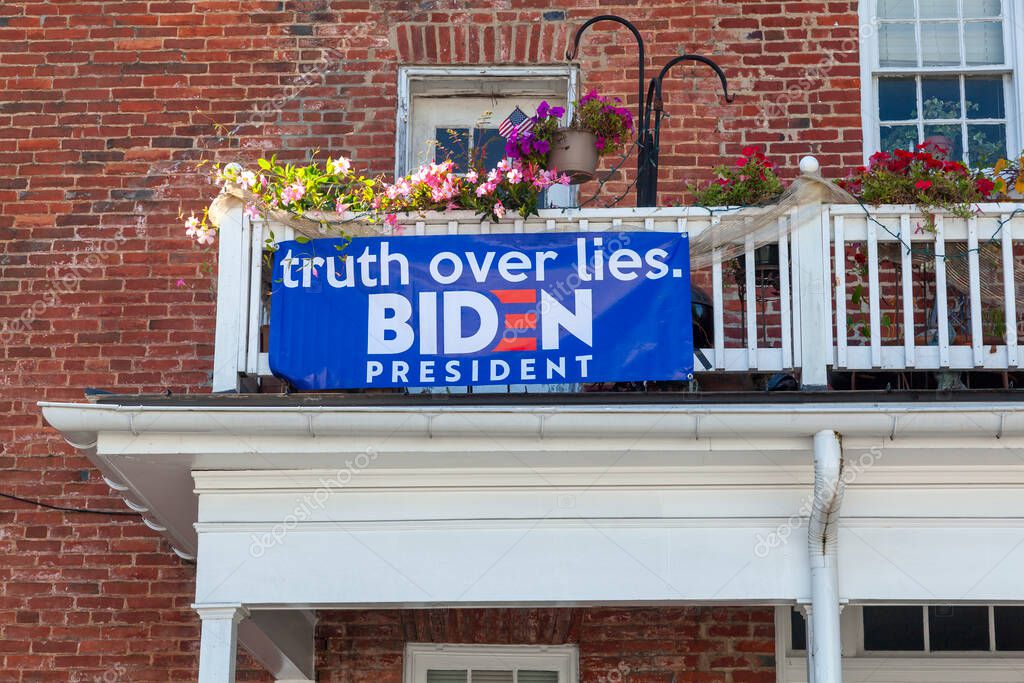 Berryville, VA, USA 09/27/2020: A blue Biden for President banner is attached to the wooden railings of the second floor balcony at a vintage brick house. It has a slogan that says 