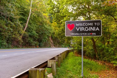 Virginia 'ya hoş geldiniz. Virjinya, Maryland eyalet sınırındaki Purcellville, Virginia' ya. Siyah tabelanın kırmızı bir kalp şekli var ve 'Virginia aşıklar içindir' sloganı altında.