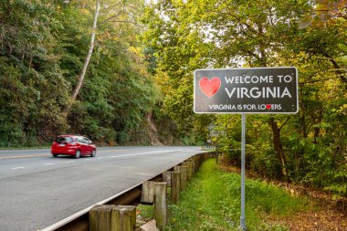 Virginia 'ya hoş geldiniz. Virjinya, Maryland eyalet sınırındaki Purcellville, Virginia' ya. Siyah tabelanın kırmızı bir kalp şekli var ve 'Virginia aşıklar içindir' sloganı altında.