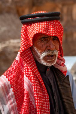 Petra, Ürdün 04 / 02 / 2010: Kırmızı keffiyeh, agal ve jubba thobe gibi geleneksel kıyafetler giyen yaşlı bir Arap 'ın portresi. Gri sakalı var. Petra yakınlarında yaşayan bir bedevi, Jordan..