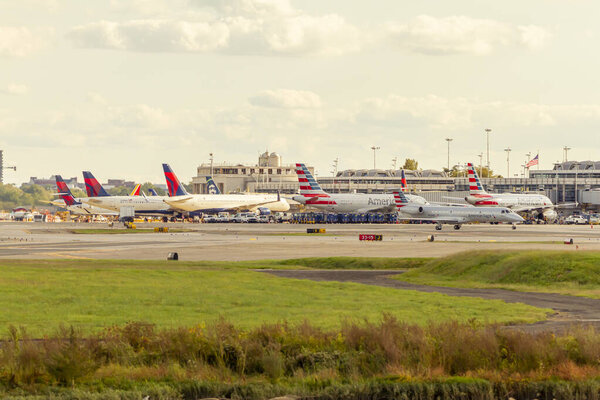 Washington DC, USA 10 / 02 / 2020: Image of planes from different airlines waiting at gates for loading and unloading in front of terminal building of Reagan National Airport. Наземный экипаж активно работает.