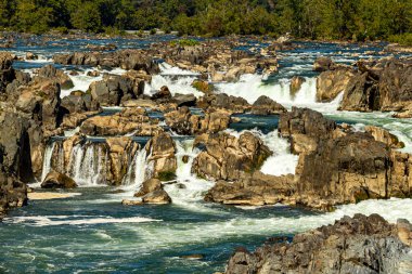 Potomac nehrinin Great Falls bölgesindeki çağlayan suyun yakın görüntüsü. Görüntü Virginia 'daki Great Falls parkında manzaralı bir manzaradan alındı. Su kayalar arasında hızla hareket ederken ışıldıyor..