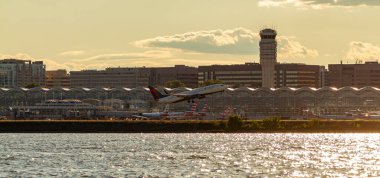 Washington DC, ABD 10 / 03 / 2020: Potomac Nehri 'nin karşısındaki Ronald Reagan Ulusal Havalimanı' nın panoramik görüntüsü. Görüntü kule, terminaller, park edilmiş uçaklar ve bir Delta Havayolları uçağının kalkış görüntülerini içeriyor..