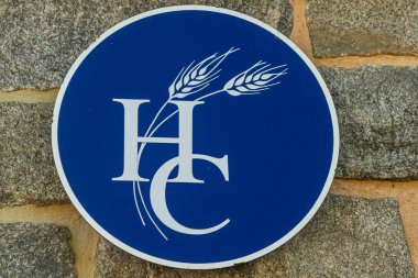 Ellicott City, MD, ABD 10 / 07 / 2020: Howard County, MD tarafından kullanılan logo bir hükümet binasının duvarında asılı. Mavi dairesel logonun üzerinde üst üste binen beyaz H C harfleri var.