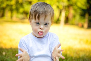 Down sendromlu doğada oynayan sevimli küçük çocuk portresi