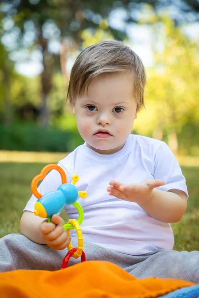 Retrato de menino bonito com síndrome de Down jogando no cobertor no dia de verão na natureza — Fotografia de Stock