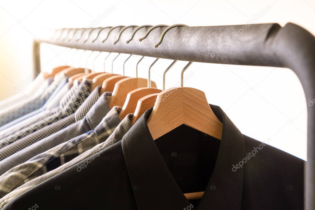 Row of mens shirts in blue colors on hanger on white background