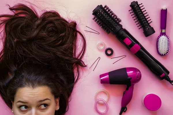 Retrato de morena e profissional ferramentas de cabeleireiro em fundo rosa — Fotografia de Stock