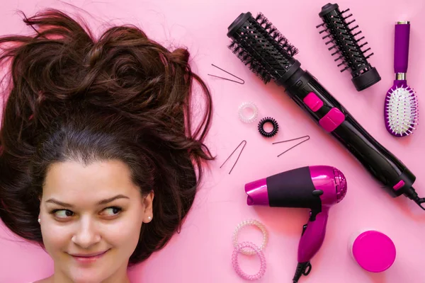 Retrato de morena e profissional ferramentas de cabeleireiro em fundo rosa — Fotografia de Stock