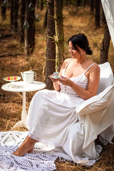 Vrouw is het drinken van koffie in de ochtend op de achtergrond van de natuur van bos — Stockfoto