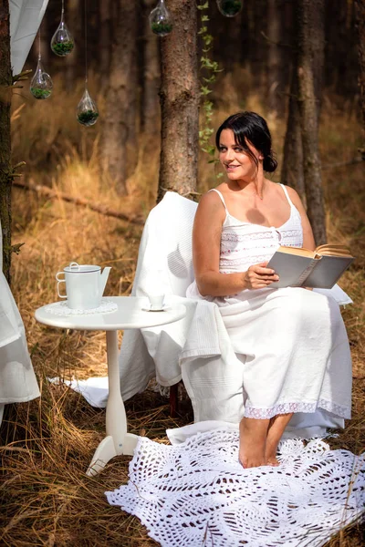 Vrouw is het lezen van boek in de ochtend op de achtergrond van de natuur van bos — Stockfoto