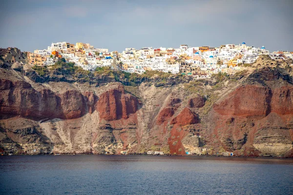 Vista del pueblo de Oia con casas blancas sobre rocas rojas caldera de la isla de Santorini, Grecia — Foto de Stock