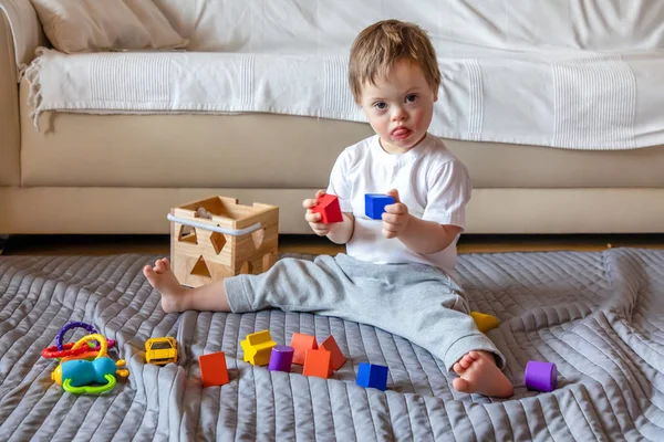 Carino piccolo ragazzo con giù sindrome giocare con giocattolo in casa — Foto Stock