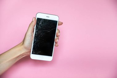 Elinde pembe bir arka plan üzerinde kırık ekran ile Smartphone
