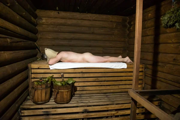 Hombre en una casa de baños rusa de madera — Foto de Stock