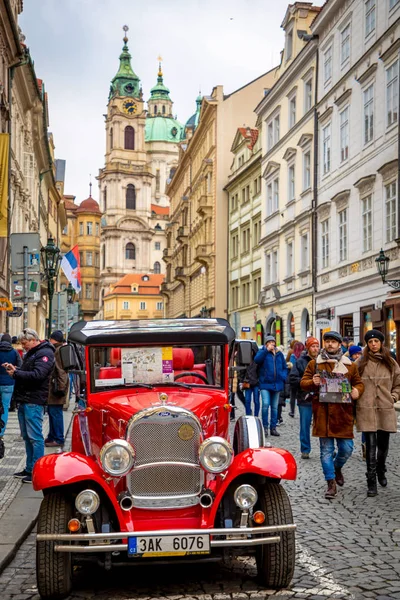 Prag, Çek Cumhuriyeti - 06.01.2019: Red retro car and Church of Saint Nicolas veya kostel svateho Mikulase, Prag, Çek Cumhuriyeti'nde insanlarla mostecka caddesinden görünümü