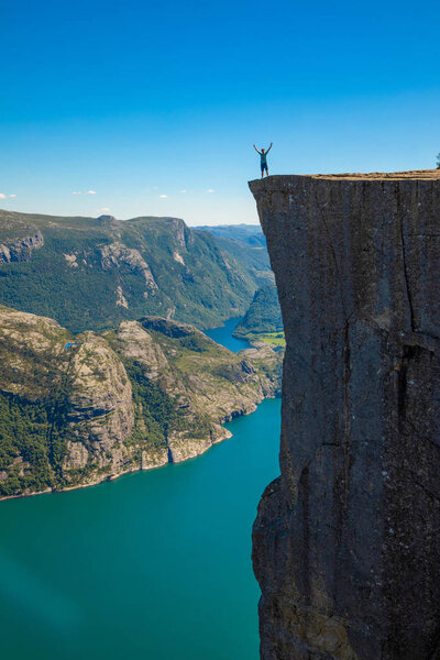 Hiker standing on Preikestolen and looking on the fjerd, Preikestolen - famous cliff at the Norwegian mountains