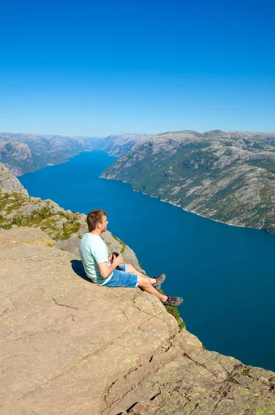 Hiker standing on Preikestolen and looking on the fjerd, Preikestolen - famous cliff at the Norwegian mountains — Stock Photo, Image