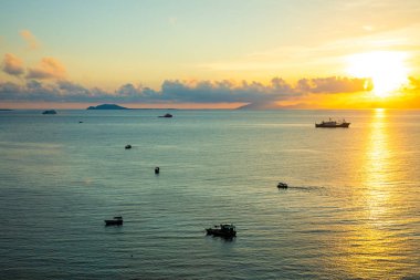 Sanya, Hainan, Çin 'de gün batımı ışıkları denizde balıkçı tekneleri