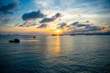 Sanya, Hainan, Çin 'de gün batımı ışıkları denizde balıkçı tekneleri
