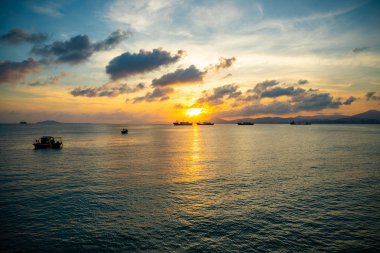 Sanya, Hainan, Çin 'de gün batımı ışıkları denizde balıkçı tekneleri