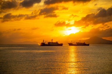 Sanya, Hainan, Çin 'de gün batımı ışıkları denizde balıkçı tekneleri