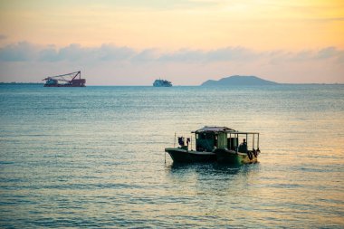 Sanya, Hainan, Çin 'de gün batımı ışıkları denizde balıkçı tekneleri