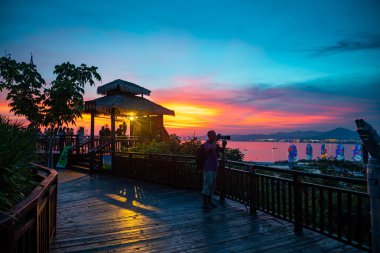 Sanya, Hainan, Çin - 7.07.2019: Gün batımı gökyüzünün arka planına karşı gözlem güvertesindeki insanlar. Hainan Adası'ndaki Luhuitou Park'tan görünüm, Çin