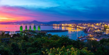 Sanya, Hainan, Çin - 7.07.2019: Phoenix adası nın ve Sanya şehrinin gece manzarası şehir ışıklarıile aydınlatıldı. Hainan Adası'ndaki Luhuitou Park'tan görünüm, Çin