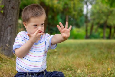 Down sendromlu şirin bir çocuk yaz günü doğada oynuyor.