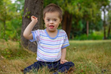 Down sendromlu şirin bir çocuk yaz günü doğada oynuyor.