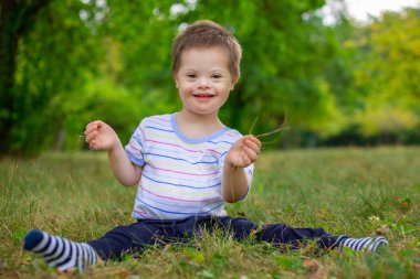 Down sendromlu şirin bir çocuk yaz günü doğada oynuyor.