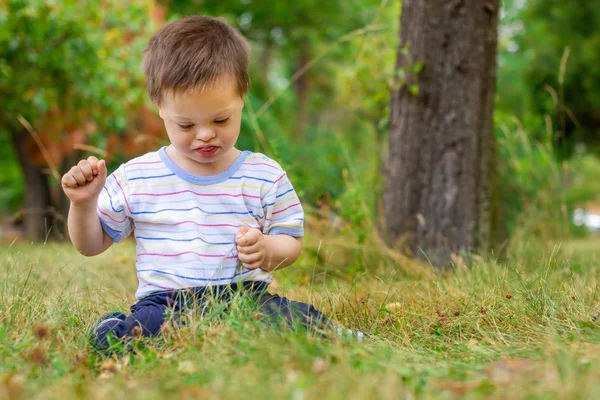 Roztomilý malý chlapec s Downovým syndromem hraje v letní den na přírodě — Stock fotografie