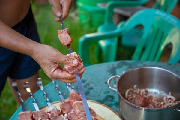 Barbeküde şiş kebap yapmak için salamura edilmiş alüminyum bir şişe et iğneleyen bir adamın eline yakın plan. — Stok fotoğraf