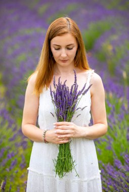 Çek Cumhuriyeti 'nde lavanta tarlasında buketle yürüyen bir kadın