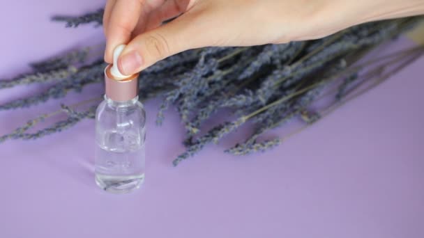 Aceite esencial de lavanda, gotas de pipeta cosmética y ramo de lavanda sobre fondo violeta — Vídeo de stock