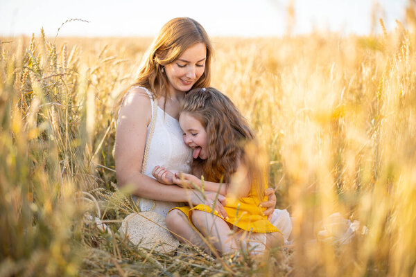 Beautiful young mother and her daughter at the wheat field in sunny day in Czech republic