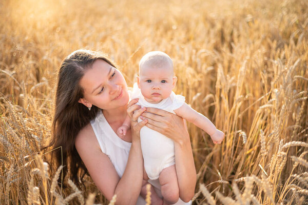 Beautiful young mother and her daughter baby girl at the wheat field in sunny day in Czech republic