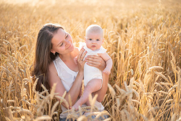 Beautiful young mother and her daughter baby girl at the wheat field in sunny day in Czech republic